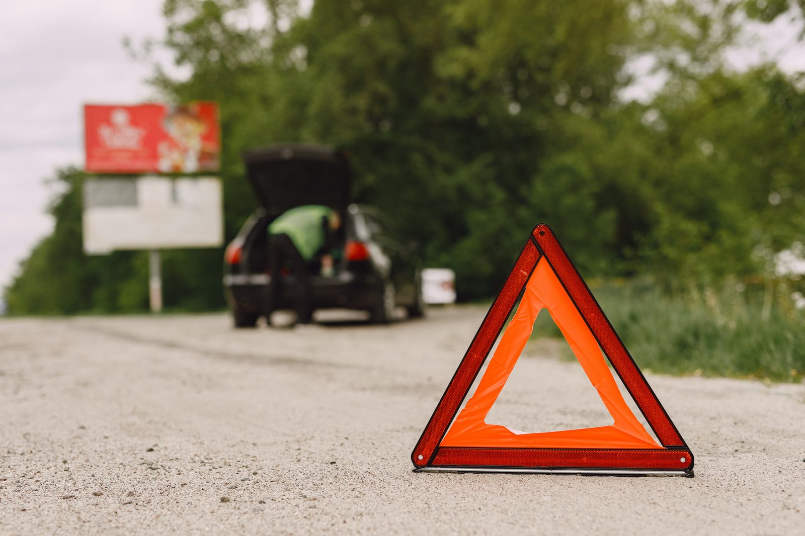 Triangolo di emergenza sulla carreggiata con un'auto ferma sullo sfondo