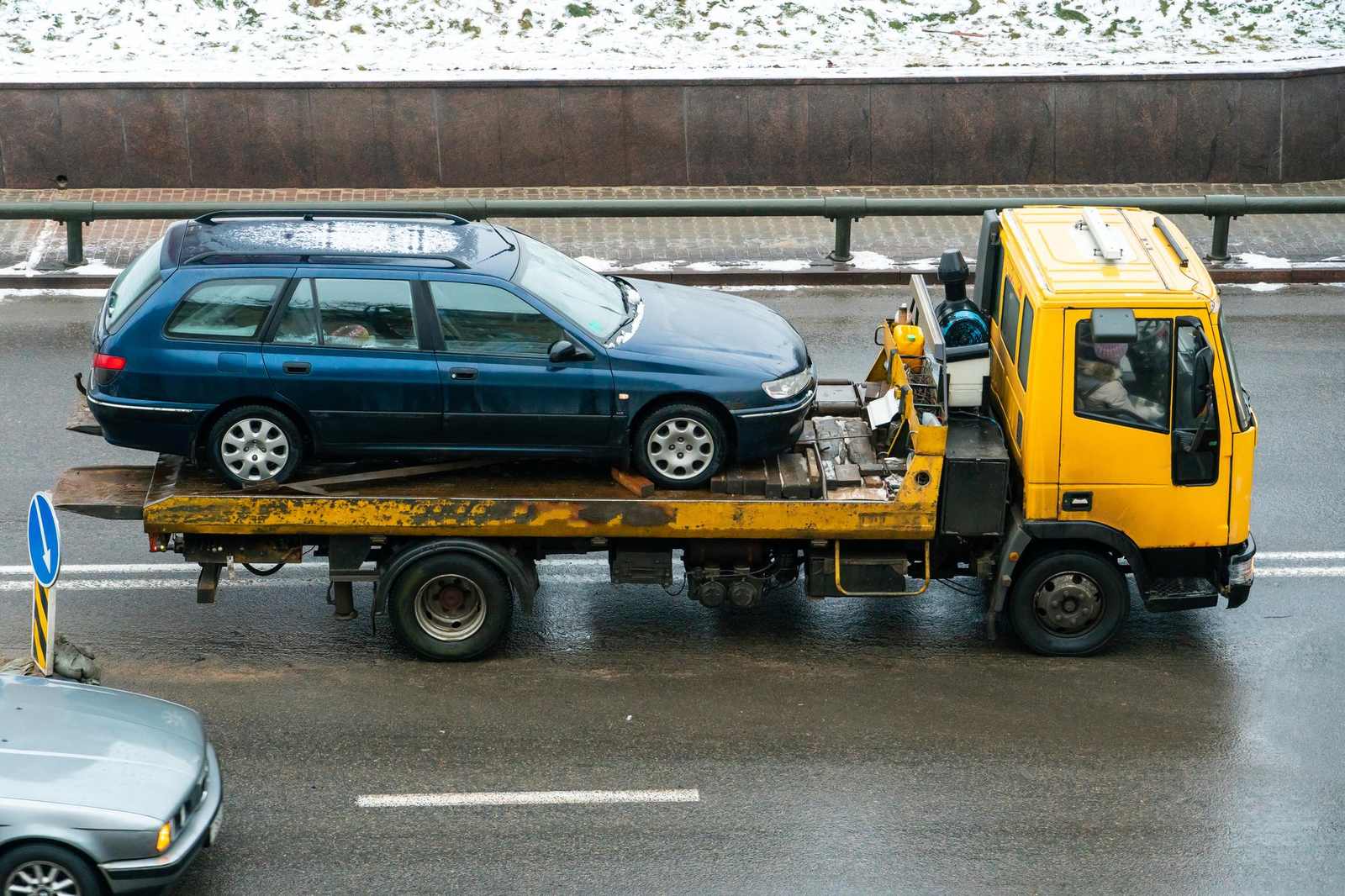 Carro attrezzi giallo con auto ancorata sul pianale