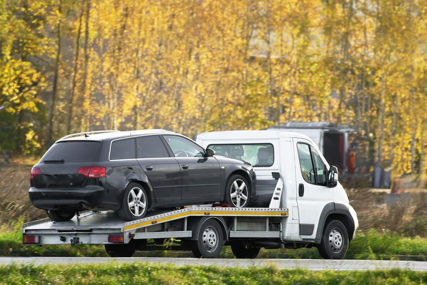 Carroattrezzi che trasporta una station wagon nera su pianale
