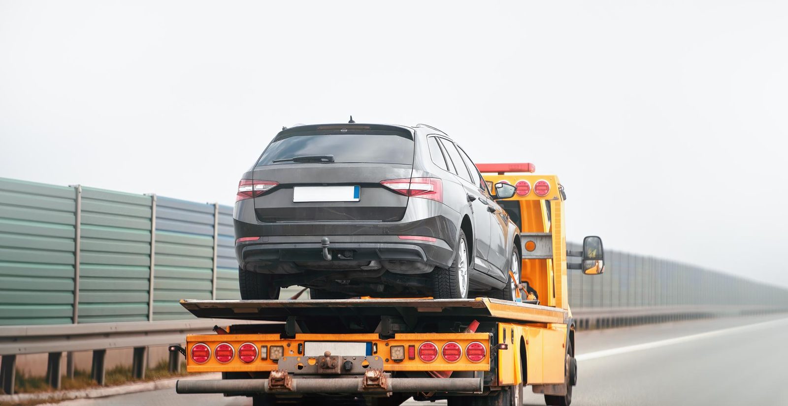 Carro attrezzi giallo con auto nera caricata sul pianale