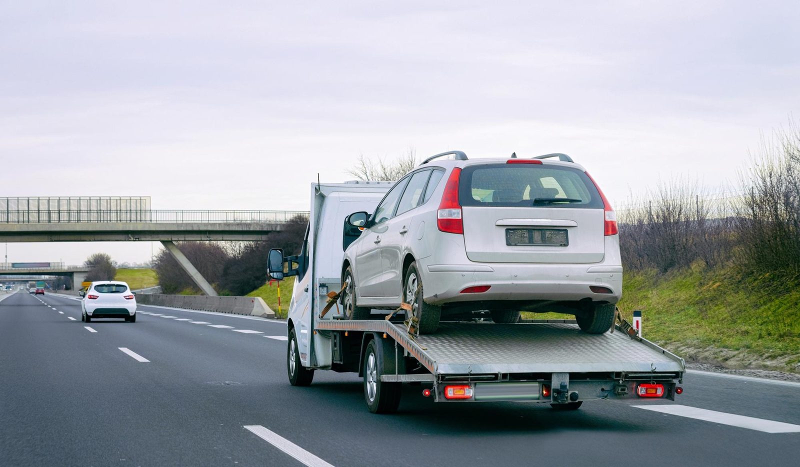 Auto argento trasportata su carro attrezzi lungo una tangenziale
