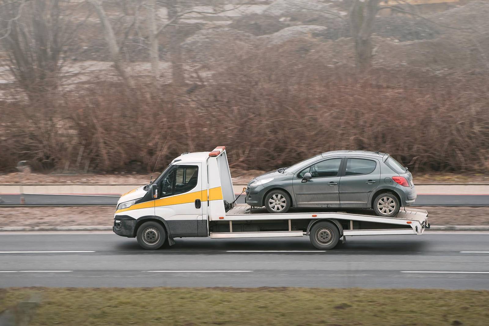 Utilitaria grigia caricata su un carro attrezzi a pianale